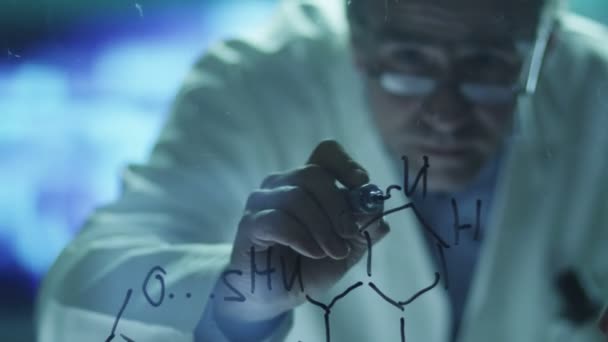 Cientista está desenhando fórmulas químicas orgânicas em vidro — Vídeo de Stock