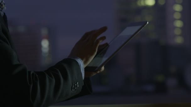 Uso de la tableta junto a la ventana grande con vista a la ciudad — Vídeos de Stock