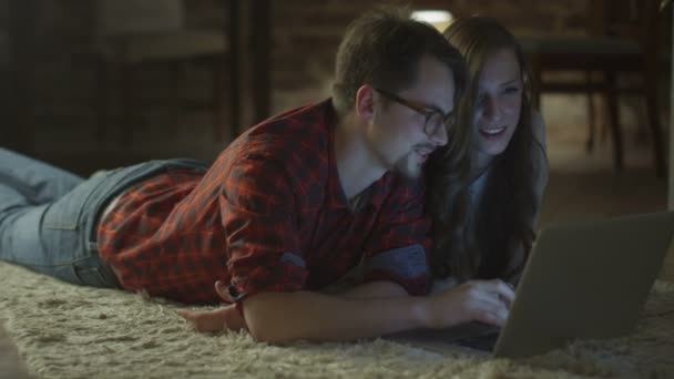 Junges glückliches lächelndes Paar mit Laptop zur Unterhaltung zu Hause am Abend. Casual Lifestyle. — Stockvideo
