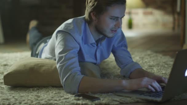 Homem jovem usando laptop em casa no horário da noite. Estilo de vida casual . — Vídeo de Stock