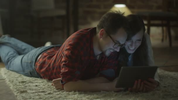 Молодая счастливая семейная пара использует компьютер для развлечения дома в свободное время. Казуальная ложь . — стоковое видео