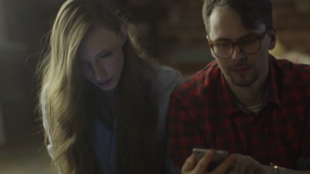 Молодая пара использует мобильные устройства дома вечером — стоковое видео