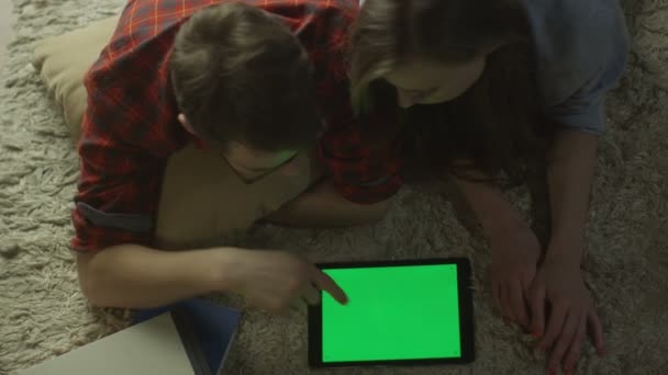 Das junge Paar nutzt zu Hause abends einen Tablet-PC mit grünem Bildschirm. Ansicht von oben. — Stockvideo