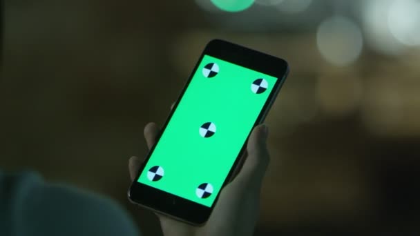 Chica joven está sosteniendo el teléfono con pantalla verde a la hora de la noche. Estilo de vida casual . — Vídeos de Stock