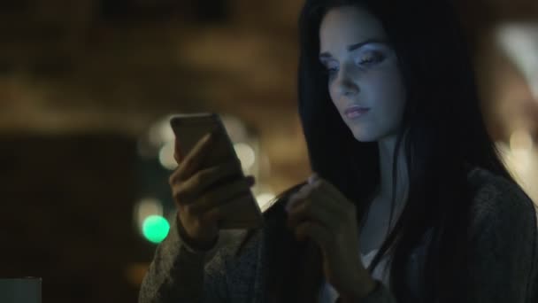 Dospívající dívka s krásným úsměvem používá smartphone v noci. Příležitostný životní styl. — Stock video