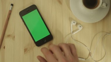 Telefon ile yeşil perde ahşap bir masa üzerinde döşeme.