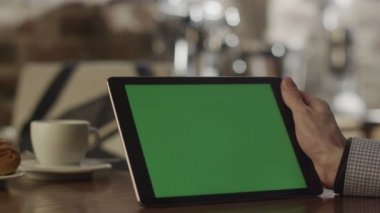 Tablet kahve dükkanında kullanan adam. Tablet ile yeşil perde.