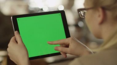 Manzara modunda yeşil ekranlı tablet kullanan kız.