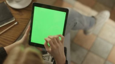 Tablet ile yeşil ekran kullanan kız. Omuz görünümü üzerinde.