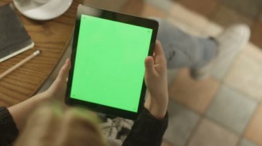 Tablet ile yeşil ekran kullanan kız. Omuz görünümü üzerinde.