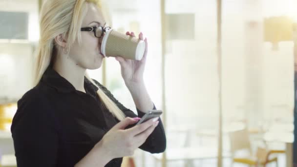 Szőke lány használ mozgatható telefon és mosolyogva — Stock videók