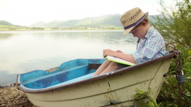 Niño leyendo un libro interesante — Vídeo de stock