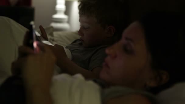 Mutter und Sohn im Bett liegend, mit Geräten — Stockvideo