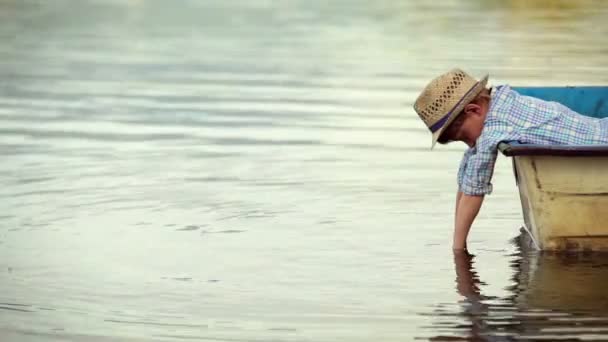 Alone little boy lies in the boat and looking in water — Stock Video