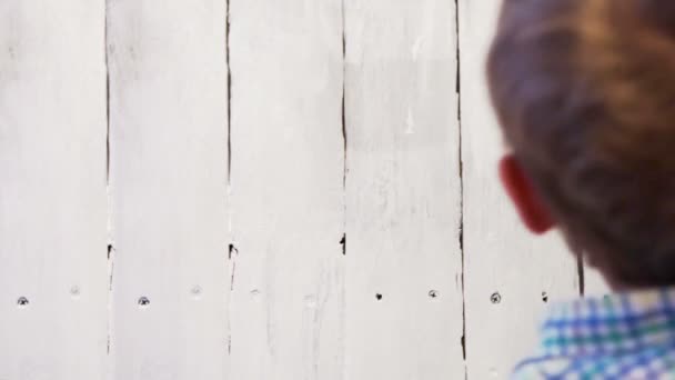 Young boy painting boardwalk fence with white color — Stock Video