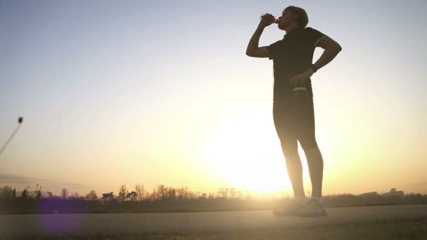 Abend-Läufer trinkt Wasser auf die Weitwinkel-Sonnenuntergang-Landschaft — Stockvideo