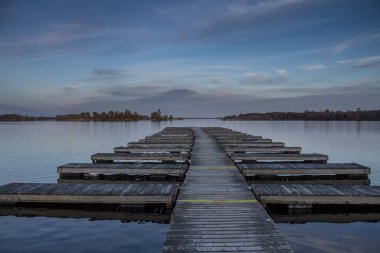 Tekne sezonu başlamadan önce arka planda güzel bir günbatımıyla boş bir rıhtımın bahar sahnesi.