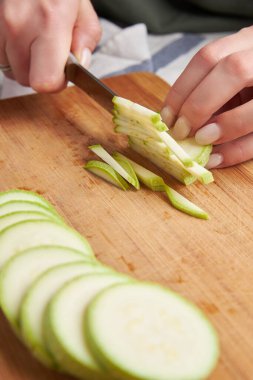 Yemek pişirmek için küçük dilimler halinde bıçakla kesilmiş eller. Yemek için kabak pişiriyorum.