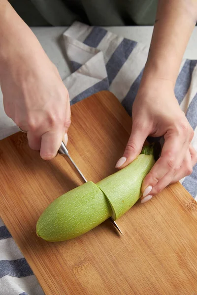 Womens hands cut with a knife green zucchini on a wooden cutting board on a blue tablecloth. cooking toast — Stock Photo, Image