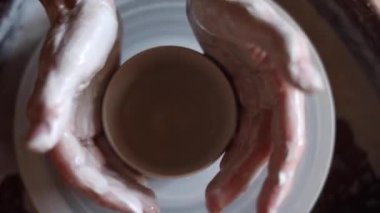 Çömlekçi çarkında kap kacak yaratmak. Eller şeklin en üstüne. Atölyede el yapımı kadın elleri. İki elinle bir vazo yap.