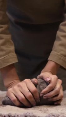 Çevre dostu gri bir çamur parçası hazırlayan bir kızın dikey videosu. Kendi atölyenizde el yapımı aletler oluşturun. Kendi işim var. Kendi ürünlerinin yaratıcı süreci