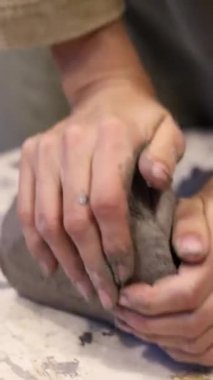 Çevre dostu gri bir çamur parçası hazırlayan bir kızın dikey videosu. Kendi atölyenizde el yapımı aletler oluşturun. Kendi işim var. Kendi ürünlerinin yaratıcı süreci