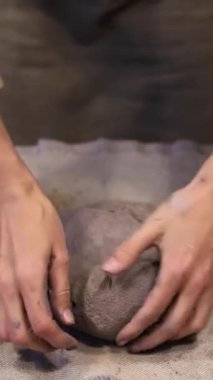 Çevre dostu gri bir çamur parçası hazırlayan bir kızın dikey videosu. Kendi atölyenizde el yapımı aletler oluşturun. Kendi işim var. Kendi ürünlerinin yaratıcı süreci