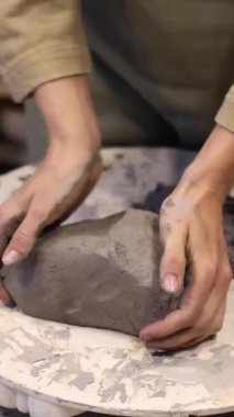 Çevre dostu gri bir çamur parçası hazırlayan bir kızın dikey videosu. Kendi atölyenizde el yapımı aletler oluşturun. Kendi işim var. Kendi ürünlerinin yaratıcı süreci