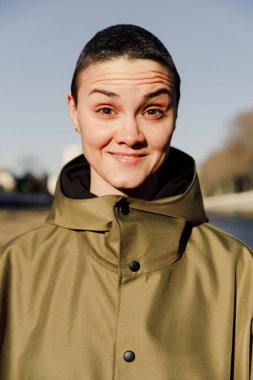 Kısa saçlı, şaşırmış bir kızın portresi. Duygusal bir fotoğraf. Sörf kıyafetleri içinde Androgenik bir kız.