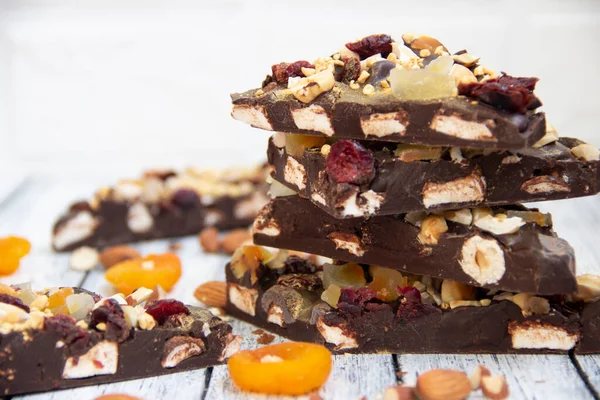 Fındıklı çikolata piramidi, marşmelov, kuru armut ve kirazlı ahşap ışıklı arka planda bulanık.