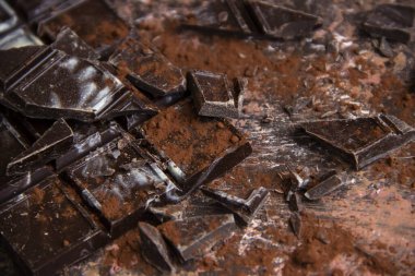 Kahverengi arka planda kakao tozu olan çikolatalı çikolata, yakın plan manzaralı.