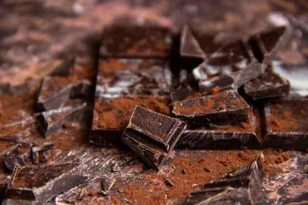 Kahverengi arka planda kakao tozu olan çikolatalı çikolata, yakın plan manzaralı.