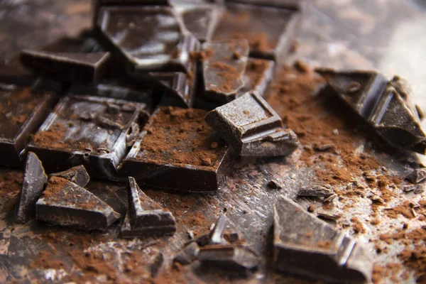 Kahverengi arka planda kakao tozu olan çikolatalı çikolata, yakın plan manzaralı.