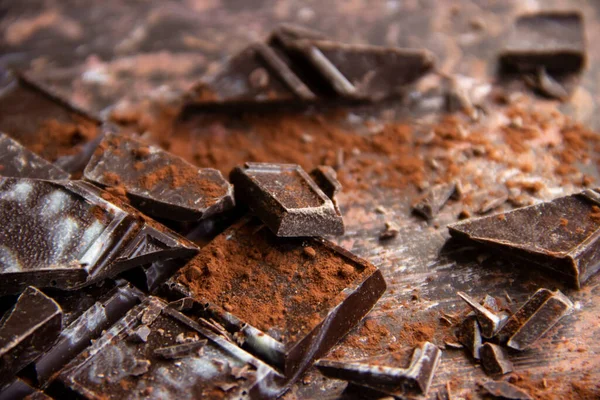 Kahverengi arka planda kakao tozu olan çikolatalı çikolata, yakın plan manzaralı.