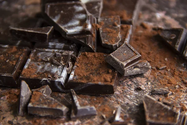 Kahverengi arka planda kakao tozu olan çikolatalı çikolata, yakın plan manzaralı.