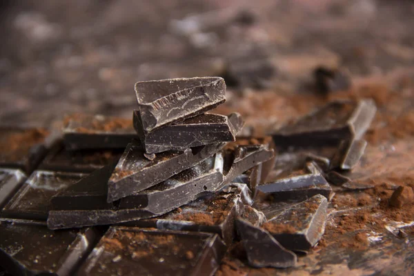 Kahverengi arka planda kakao tozu olan çikolatalı çikolata, yakın plan manzaralı.