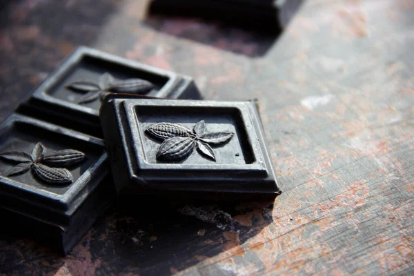 Koyu çikolata parçaları, güneş tarafından aydınlatılan koyu bir arkaplanda.