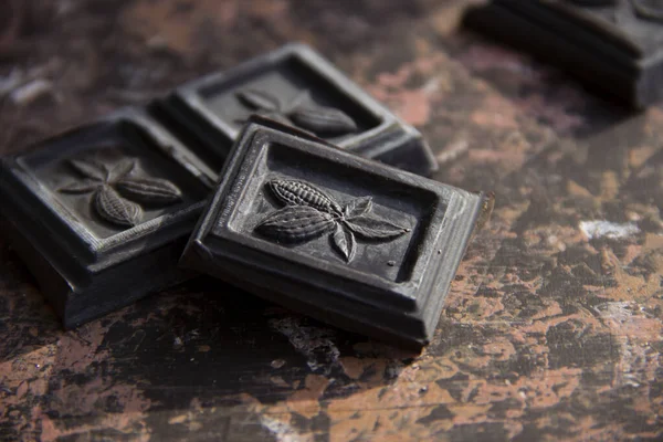 Koyu çikolata parçaları, güneş tarafından aydınlatılan koyu bir arkaplanda.