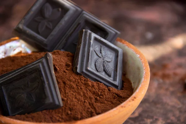 Kil bardaktaki acı çikolata. Arka planda bulanık kakao. Yakın plan.