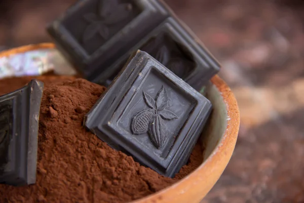 Kil bardaktaki acı çikolata. Arka planda bulanık kakao. Yakın plan.