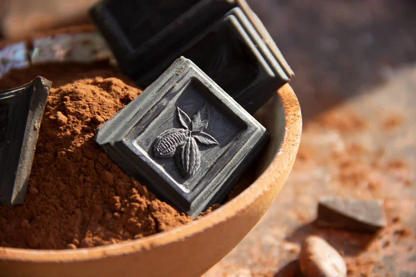 Kil bardaktaki acı çikolata. Arka planda bulanık kakao. Yakın plan.