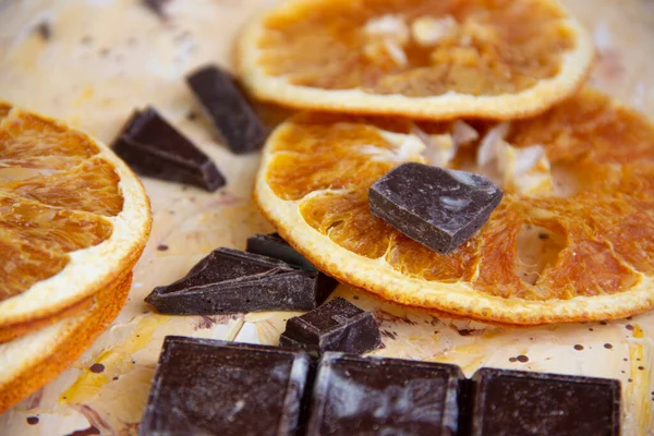 Kurumuş portakal dilimleri ve siyah çikolata parçaları. Kapalı bir arka plan, yakın çekim.