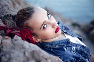 Mavi gözlü, parlak dudaklı ve saçlı güzel bir genç kız. Arkaplan sanatsal amaçlar için bulanık.