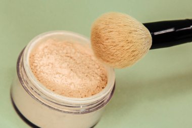 Yeşil arka planda izole edilmiş gevşek toz ve büyük fırça ile kutu.