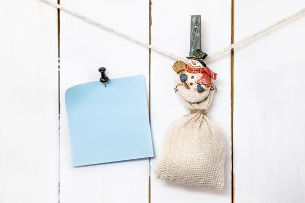 Christmas snowman wasknijper holding zak en vastgemaakte Opmerking papier — Stockfoto