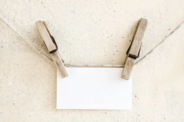 Прищіпки, що тримають чисту білу паперову картку — стокове фото