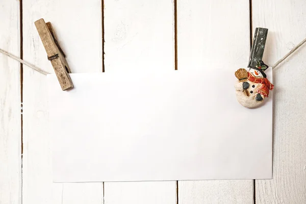 Різдвяні прищіпки сніговика тримають білу паперову картку — стокове фото