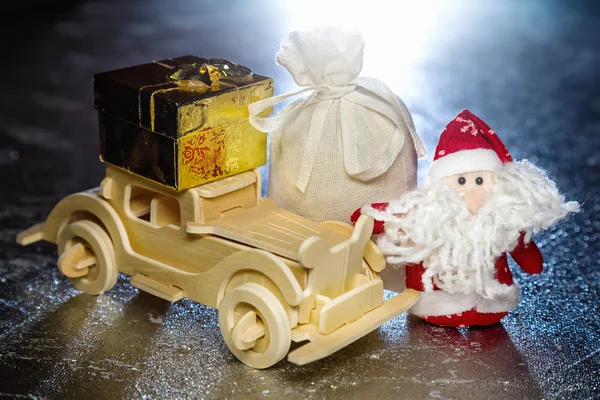 Santa Claus s dřevěnými auto, dárkové krabice a pytel — Stock fotografie