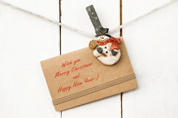 Christmas snowman clothespins holding greeting card — Stock Photo, Image