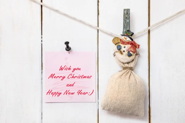 Snowman clothespin holding sack and Christmas greeting note — Stock Photo, Image